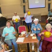 A seated dance exercise with sparkly bowler hats